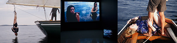 The first of three photos depicts the stern of a sailboat on water, with one crewperson visible aboard. A woman, tied upside down by her feet to the boom, hangs above the water, her long dark hair barely skimming the surface. A land mass can be seen far off in the distance behind her. The second image shows two video monitors, one large and one small. On the large monitor two women in black tank tops stand in water up to their waist. The third image is a closely cropped view of two people in the stern of a wooden boat at sea. The legs of a man in black swim trunks stand above a long, wavy haired strawberry-blonde woman in a blue patterned outfit. She lies on her back, her head tilted backwards, her right arm encircling the man's left leg, her left arm clutching the gunwale, her pale bare thighs visible behind and between the man's darker legs.