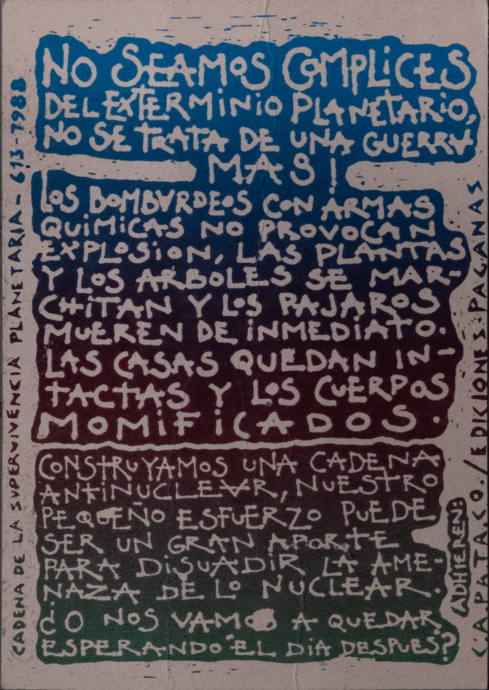 A silk screened anti-war poster in dense, hand written text in Spanish that blue at the top, and fades to purple and green ombré. It calls for resistance to nuclear war.