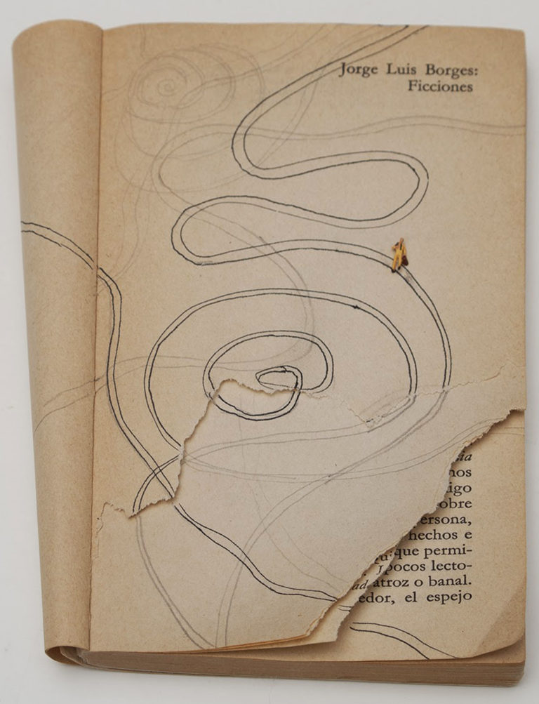 A photo of a paperback book with its cover folded back behind it revealing the title page, which is torn. The title of the book is in the upper right hand corner: Jorge Luis Borges: Ficciones. There is a looping drawing of parallel lines across the page with a tiny toy figure attached.