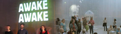 Two photographs of performances from left to right: 1) a large block-lettered sign that reads "AWAKE AWAKE" and glows white and green is suspended behind three blurred figures sitting in the foreground. 2) A crowd of people stands and sits in a room filled with fog.